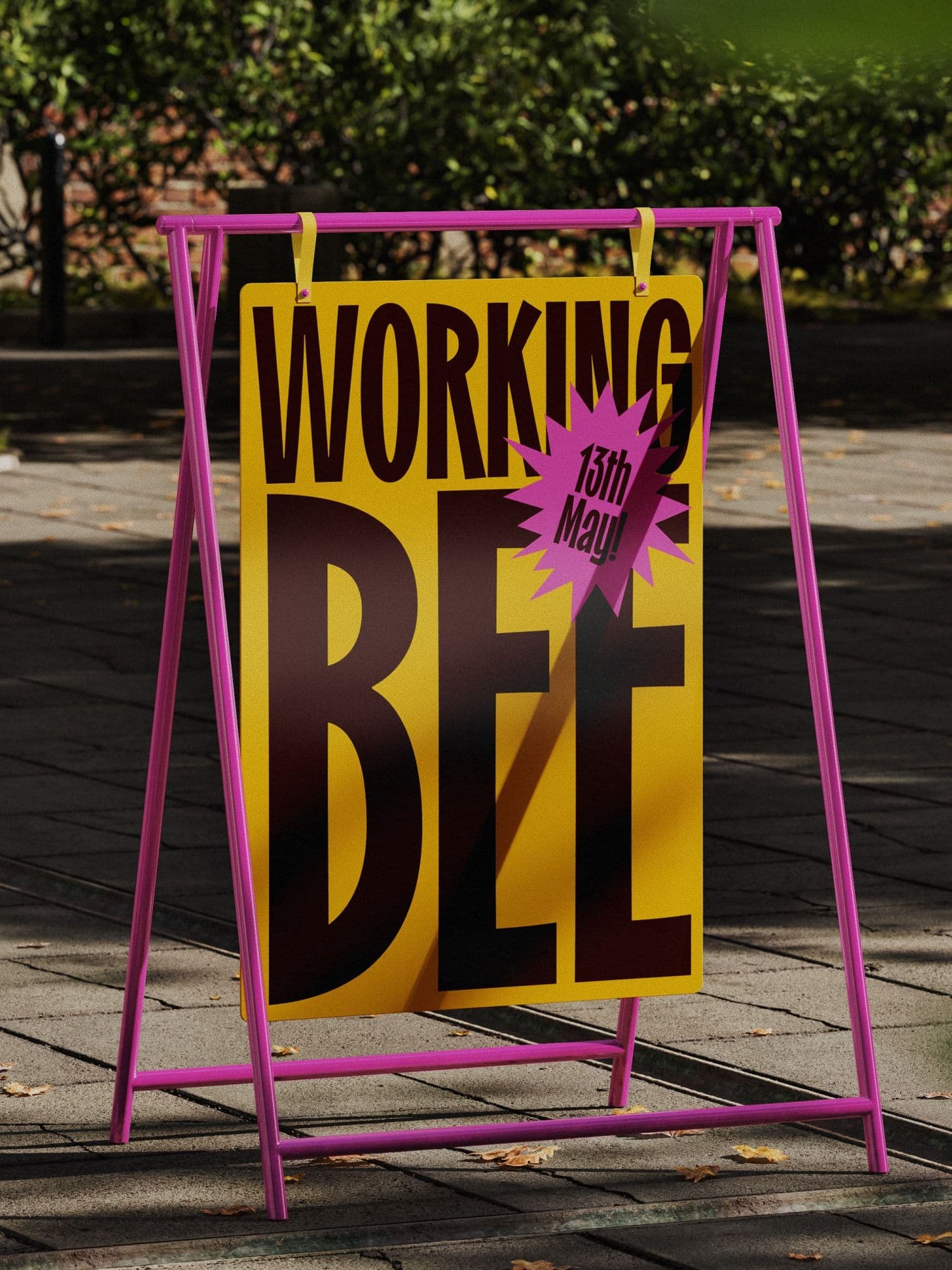 Outdoor yellow A-frame sign with magenta frame reading WORKING BEE and a pink starburst dated 13th May, on a sunny paved garden path.
