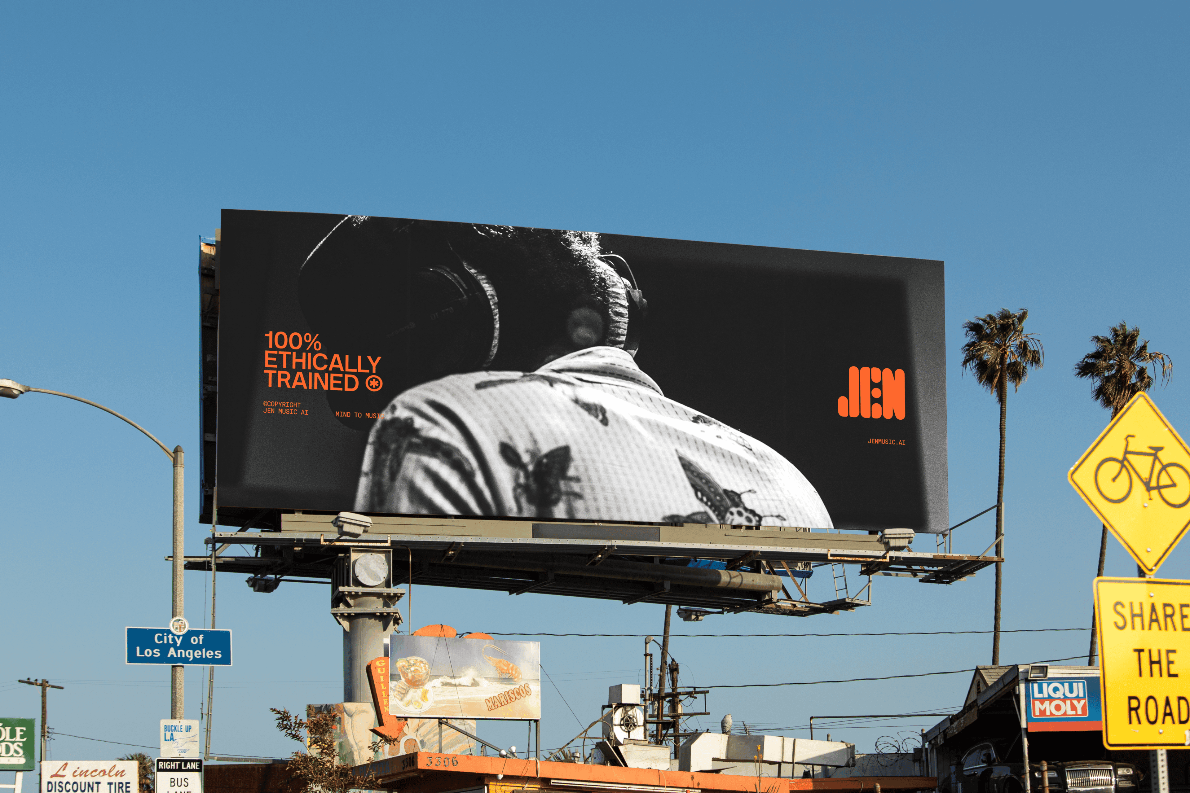 A JEN “100% Ethically Trained” billboard above a sunny Los Angeles street with palm trees and a “Share the Road” sign.